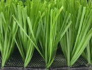 Bright green artificial turf close-up. Synthetic grass blades texture detail over black mesh base.